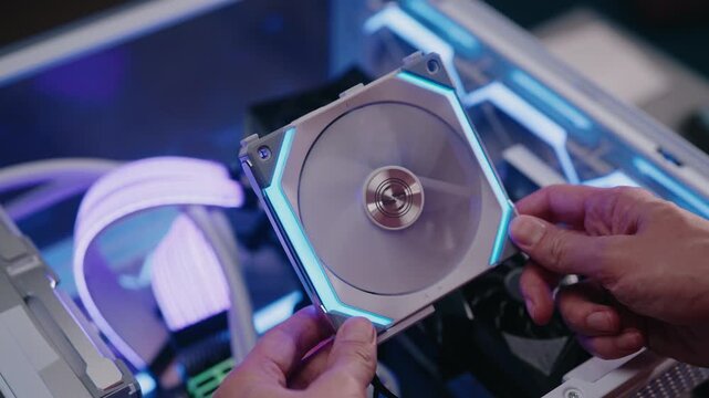 Computer engineer hands installing high performance rgb cooling fan into custom built desktop pc, enhancing airflow and system aesthetics with colorful lighting, close-up, slow motion.