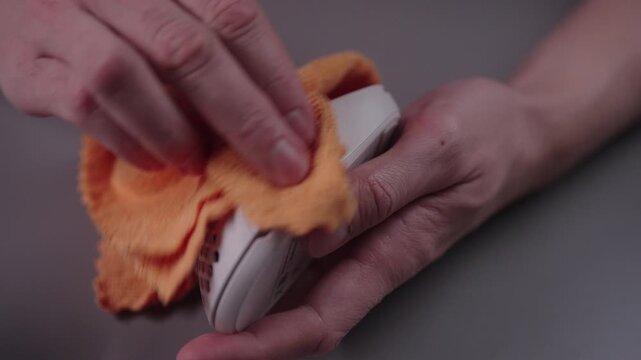 Professional sanitizing and wiping computer mouse with disinfectant spray and microfiber cloth, concept of hygiene and cleanliness in modern office, close-up. Shooting in slow motion.