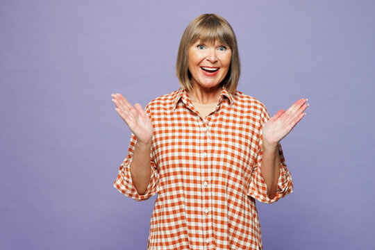 Smiling elderly gray-haired woman 50s years old wearing casual clothes keep mouth open spreading hands surprised look camera isolated on pastel plain pastel light purple color wall background studio.