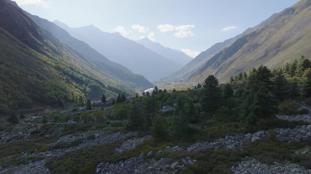 Cinematic drone orbit over rocky terrain and pine trees revealing the deep Baspa River valley in Kinnaur.