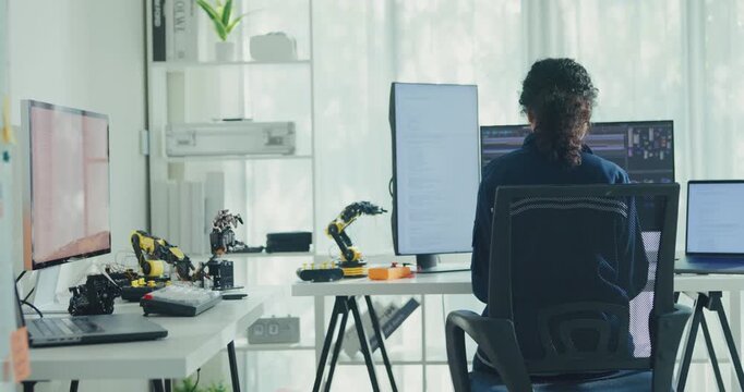 Young African American female robotics engineer coding AI software for robotic arm in laboratory. Embedded system, firmware testing, machine learning, industrial automation, future technology concept.