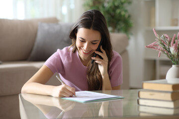 Happy woman signing contract making phone call