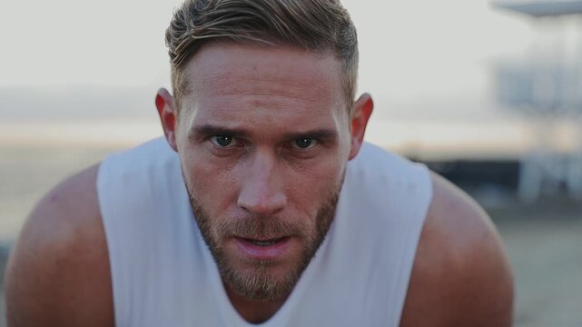 Close up young tired strong sporty athletic fit sportsman man wear white sports clothes taking respite breathe warm up train at sunrise sun over sea beach outdoor on pier seaside in summer day morning