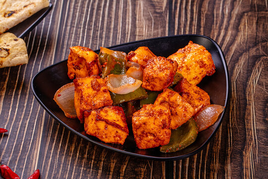 Indian Paneer Tikka Masala inl with Roti bread on a dark wooden table