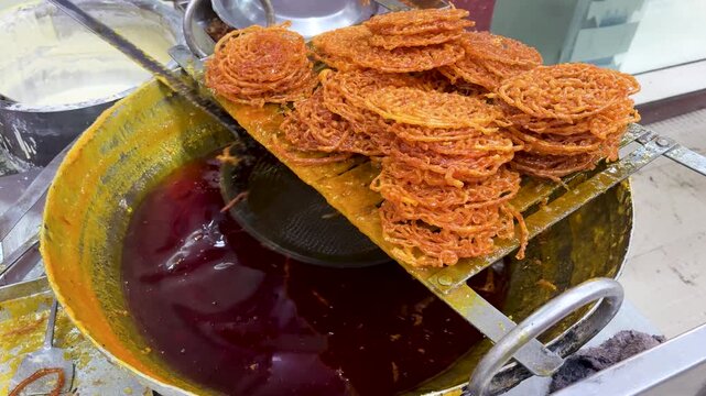 fresh jalebi dipped in sugar syrup stacked on tray indian street sweet preparation close up