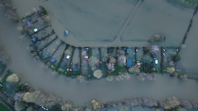 Top down aerial shot of flooded houses and plots in Sarthe department showing brown water surrounding properties and bare trees