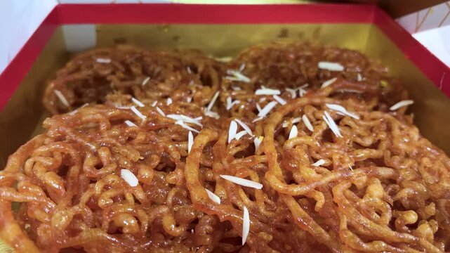 close up of juicy jalebi with sugar syrup and nuts topping