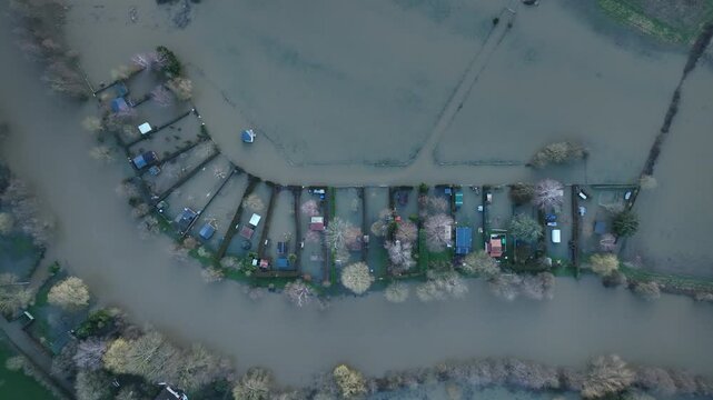 Top down aerial view of flooded residential area in Sarthe department with houses gardens and trees partially submerged in brown water