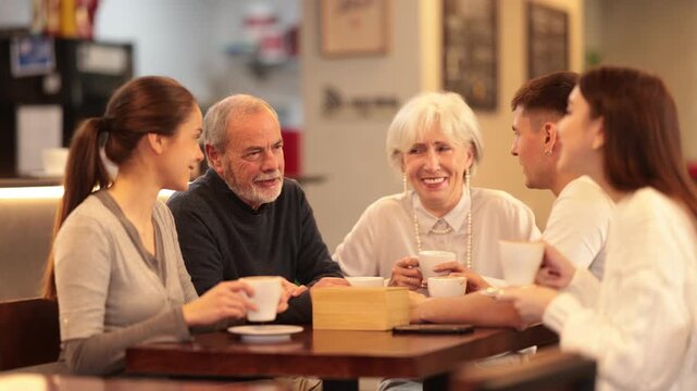 In cozy restaurant, young family and mature parents enjoy festive lunch, celebrating important event. High quality 4k footage
