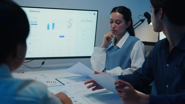 Asia businesspeople presentation sales meeting plan statistics brainstorm and work with paperwork around table in office conference room at night. Business finance partner strategy investment success.