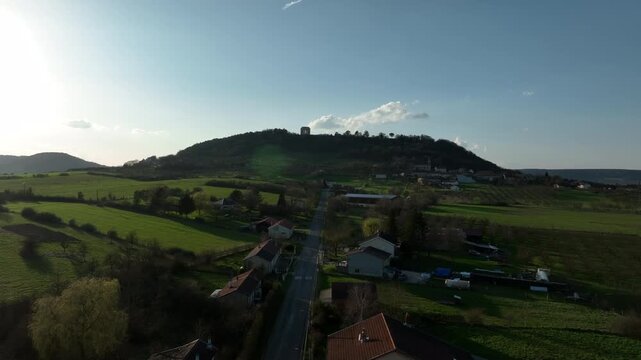 Aerial view of Butte de Montsec monument in Meuse department overlooking a village with road fields and green hills under bright sunny sky