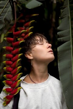 Woman with Short Hair Eyes Closed Leaning Back Near Heliconia Flower