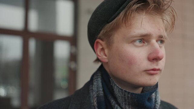 Closeup of young white creator with hopeful gaze beret and scarf damp with drizzle, detailed skin texture and blue eyes, soft shallow depth, emotive cinematic portrait of visionary dreamer