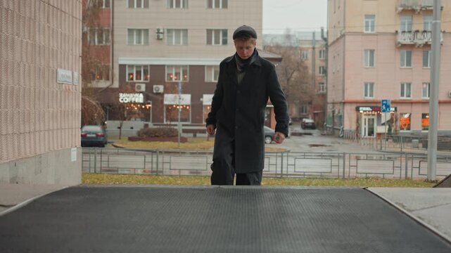 Young caucasian creator standing in rain on urban steps, approaching doorway, coat and scarf soaked, beret tilted, contemplative gaze toward sky, cinematic color grading, subdued autumn atmosphere,
