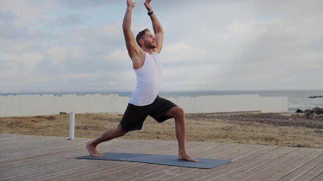 Young calm strong sporty athletic fit sportsman man wear sports clothes do yoga exercises squat breathe warm up train at sunrise sun dawn over sea beach outdoor on pier seaside in summer day morning