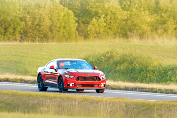 Fototapeta premium Customized red roadster driving on asphalt highway