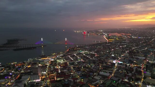Cinematic aerial drone shot of Cebu City at sunset, showcasing the urban skyline as city lights begin to glow at dusk