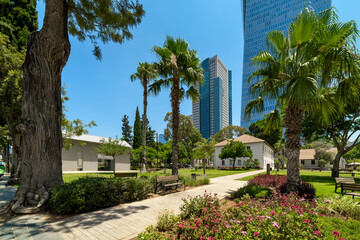 Green public space among trees and palms with skyscrapers on the background in Sarona Park in Tel Aviv, Israel. © Rostislav Glinsky