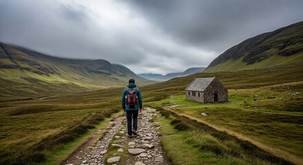 Obraz premium Solo Male Hiker on a Spiritual Pilgrimage Path Towards a Remote Stone Chapel in Misty Highlands