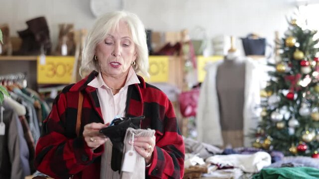 Uncertain old lady looking for gloves during X-mas sell-out season in retail outlet