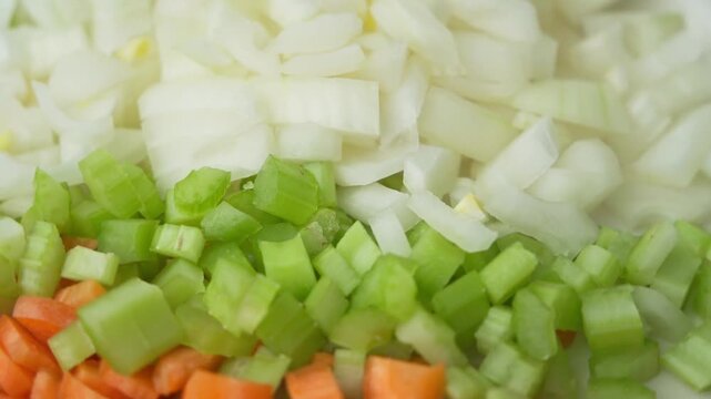Diced Italian soffritto ingredients onion celery and carrot rotating close up