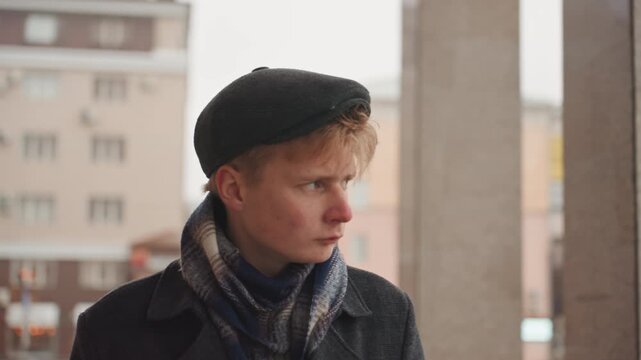 Youthful artist thinking. Aspiring creator pauses near architectural columns. Youthful artist in winter attire stands contemplatively beside building pillars while envisioning new concepts