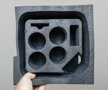 Close up POV of 3D printed polystyrene foam insert with custom cut compartments for product packaging protection isolated on neutral background