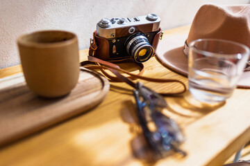 A camera, coffee, and a hat are on the table. A table in a cozy coffee shop. Weekend walk. © zhukovvvlad