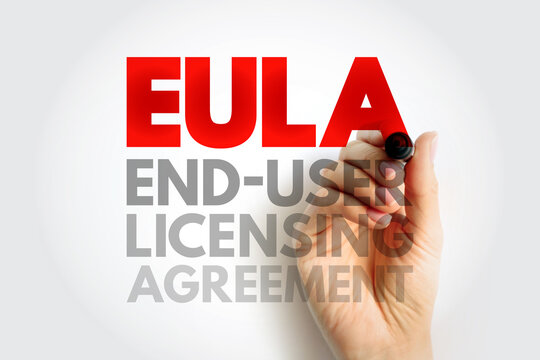 EULA END-USER LICENSING AGREEMENT text on white paper held by a hand with a pen, representing digital software license, legal rights, compliance, and technology documentation