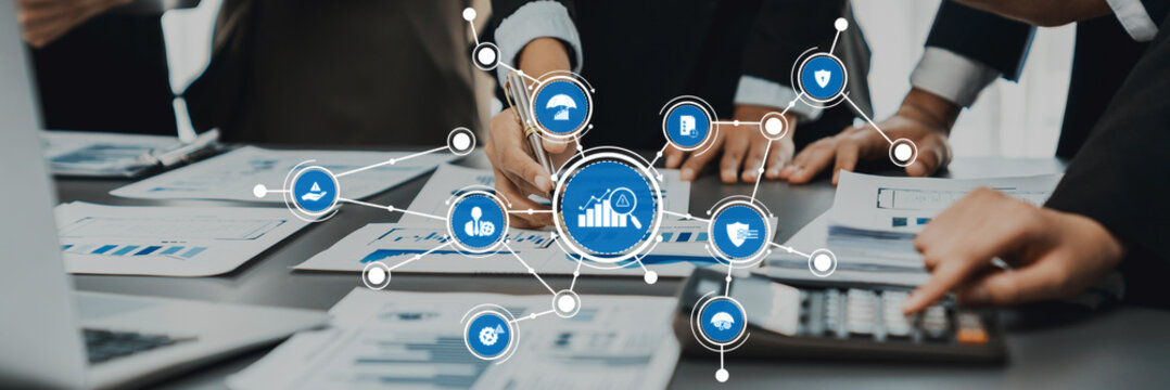 This stock photo captures a modern office setting where business professionals engage in management activities, featuring graphs and digital icons for effective collaboration and strategy. Amity