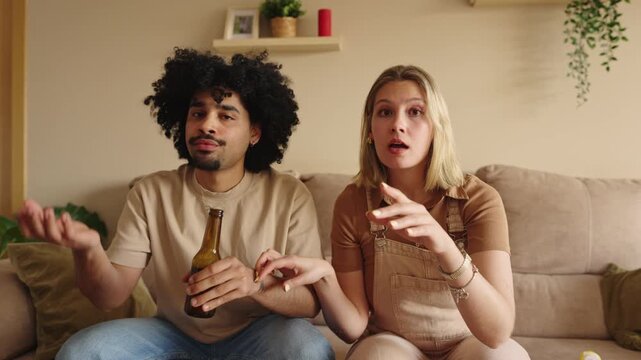 Disappointed couple showing sad emotions watching sports game on tv - missed penalty in football