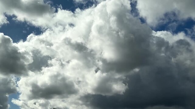 Beautiful white fluffy cumulonimbus clouds mixing and churning with darker storm clouds in timelapse mode.