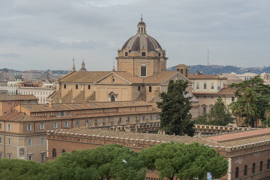 Elevated view from Capitoline Hill showing Rome architecture, Italian pine trees and the dome of Santa Maria in Aracoeli. Calm city scene in cloudy weather.