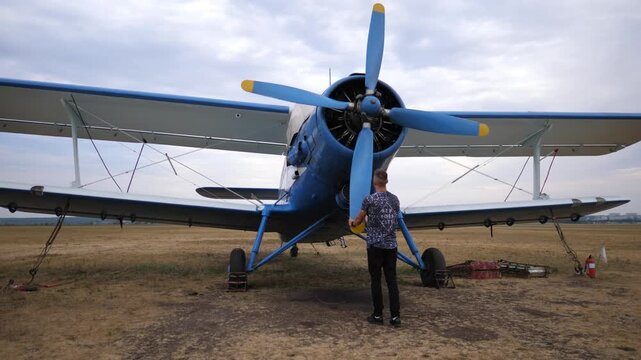 Plane pilot inspecting the propeller of a blue aircraft, showcasing the meticulous pre-flight check process, emphasizing attention to detail and safety in aviation operations
