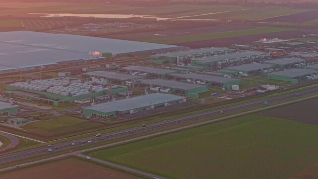 Aerial shot of a large industrial data center campus at sunrise, with a highway alongside. Big data and cloud computing server farms concept