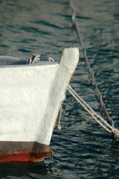 A close up view shows the white bow of a traditional wooden boat moored in the calm sea of the island of Mljet