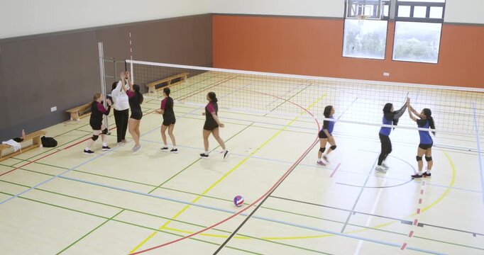 Rally ending sending Maroon women huddling left on court, official, ball resting center, copy space