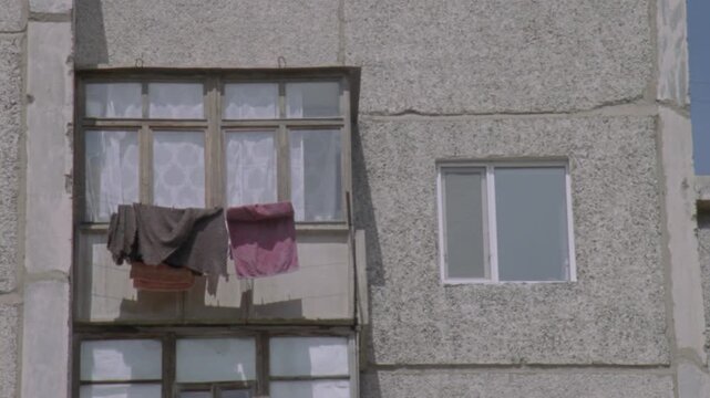 Old soviet apartment building with laundry drying on a balcony in a gentle breeze