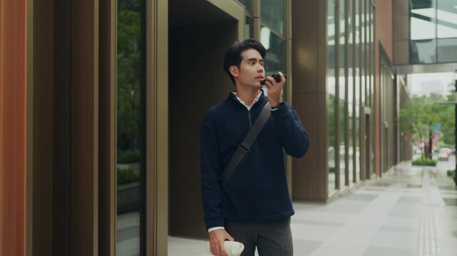 Young office worker steps out for a midday reset, talking on his smartphone during lunch, reflecting modern work life where flexible hours and soft hustle define the new concept of corporate life
