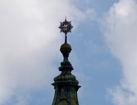 Historic rooftop adorned with weathered copper. Cloudy sky highlights ornate copper spire with star