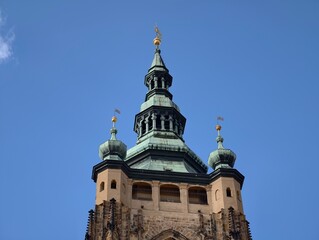 Fototapeta premium Gilded finial atop copper structure shines. Architectural cupola with detailed patina under clear skies