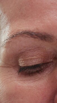 Close up portrait: old eye female, macro. Beauty senior woman with grey hair open eyes. Retired lady looks up, wrinkles skin. Eyesight or vision. Grandma lifts her eyelids, looking and blinking