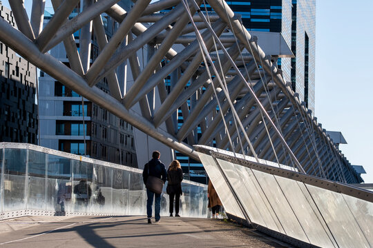 People walking across the Akrobaten pedestrian bridge in Oslo Norway with modern Barcode architecture and strong steel perspective lines