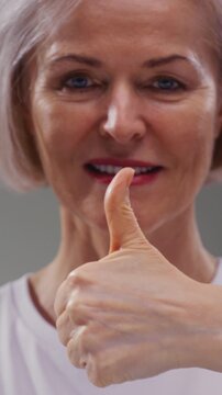 Like portrait: senior elderly mature woman, 60-80s, giving thumbs up hand gesture sign, smiling. Old female shows a like with her hand or palm. Good great news, positive feedback.
