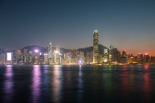 Panoramic night view of Victoria Harbour cityscape in Hong Kong, China, showcasing  skyline illuminated by colorful lights from skyscrapers, banks, shopping centers and residential buildings.