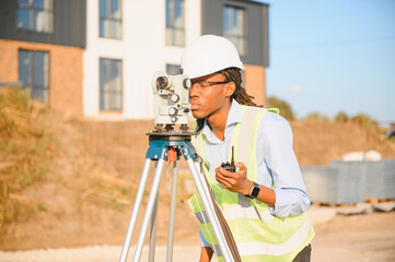 Naklejka premium African american surveyor working with theodolite on construction site