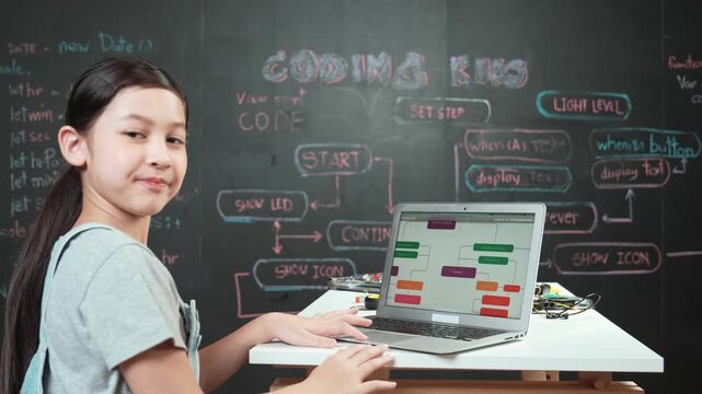 high school girl waving hand while sitting at blackboard with engineering code or prompt written. Young academic student greeting and looking at to camera .Creative education concept. Edification