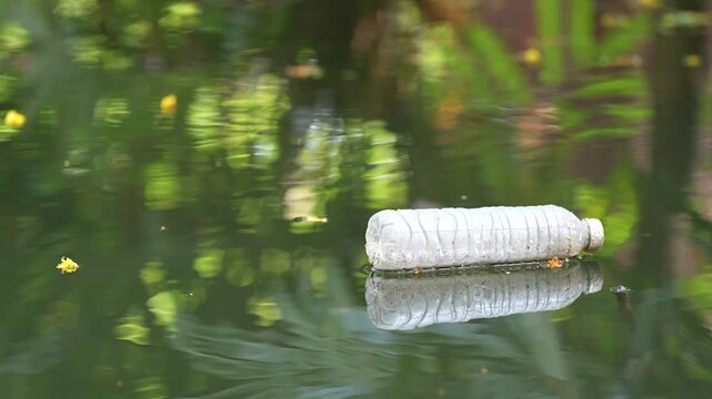 Plastic bottle floating in polluted water, litter and trash in green pond, waste pollution and environmental damage