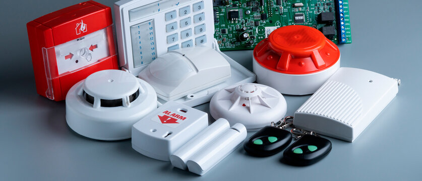 Different types of fire and security alarm equipment on a gray surface