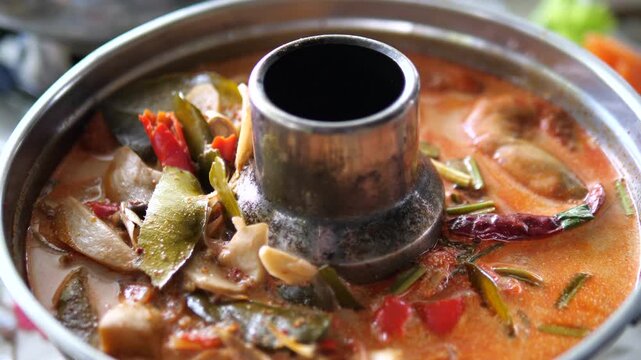 Authentic creamy Tom Yum Kung spicy seafood soup in traditional Thai hot pot for restaurant and Asian cuisine concept